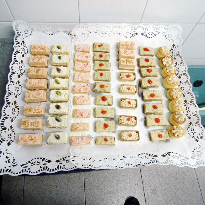 Una bandeja de sándwiches sobre una servilleta de encaje blanco.