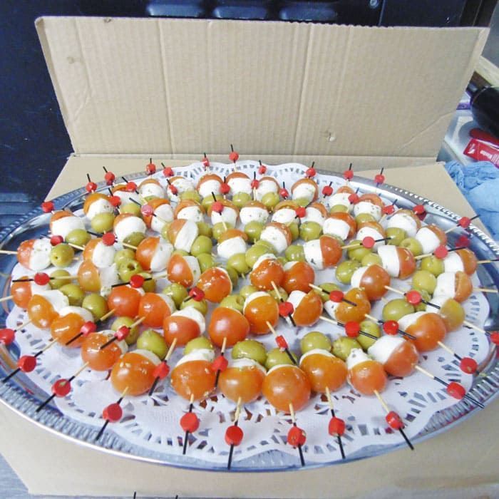 Un plato de comida con tomates y aceitunas en brochetas.