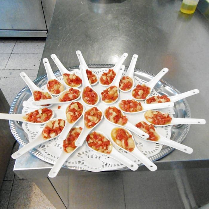 Una bandeja de cucharas llenas de comida sobre una mesa.