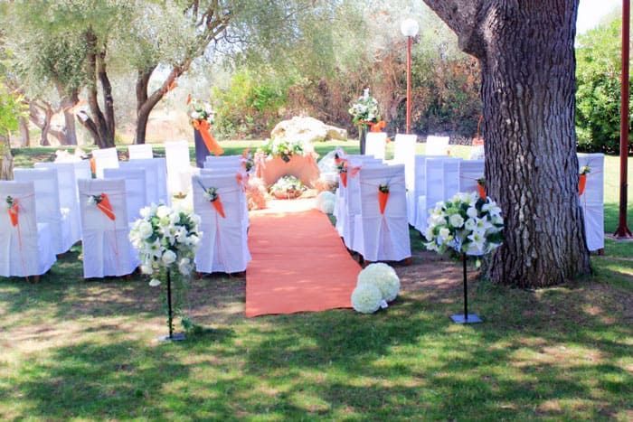 Se está celebrando una ceremonia de boda en un parque con sillas y flores.