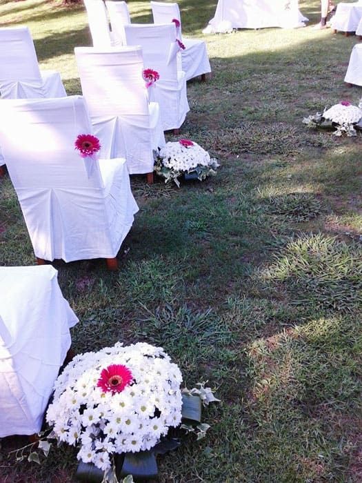 Una fila de sillas blancas con flores en el suelo.