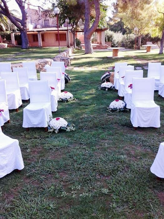Una fila de sillas blancas están alineadas en un exuberante campo verde.