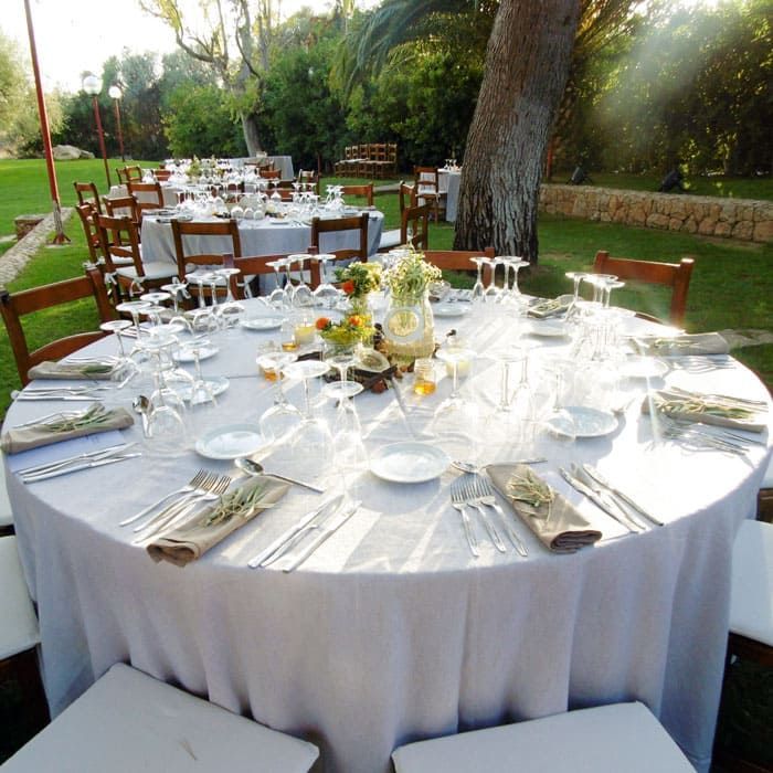 Una mesa redonda con un mantel blanco y vasos encima.