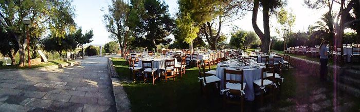 Una vista panorámica de un parque con mesas y sillas preparadas para una recepción de boda.