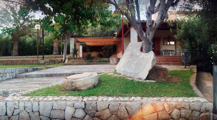 Una gran roca está sentada en el césped frente a una casa.