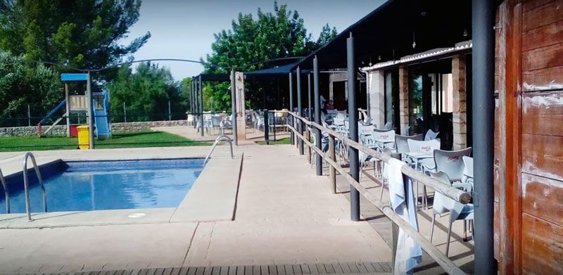 Una gran piscina está rodeada de mesas y sillas.