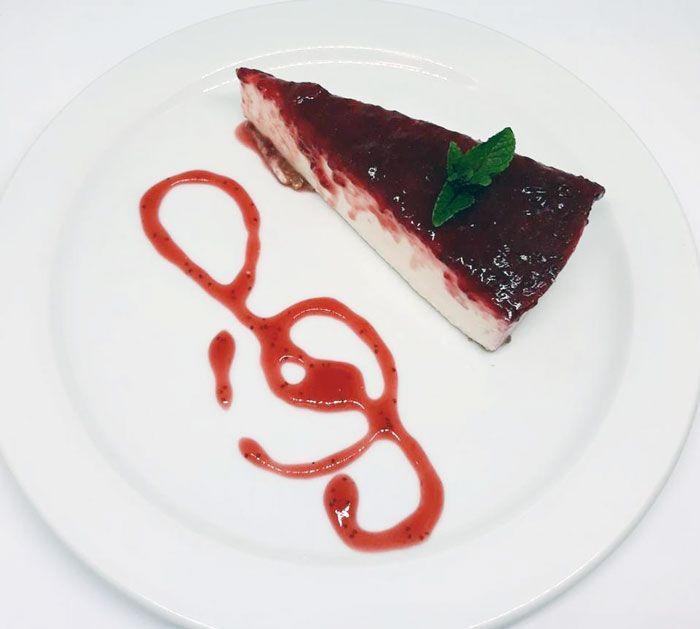 Un plato blanco cubierto con una rebanada de tarta de queso.