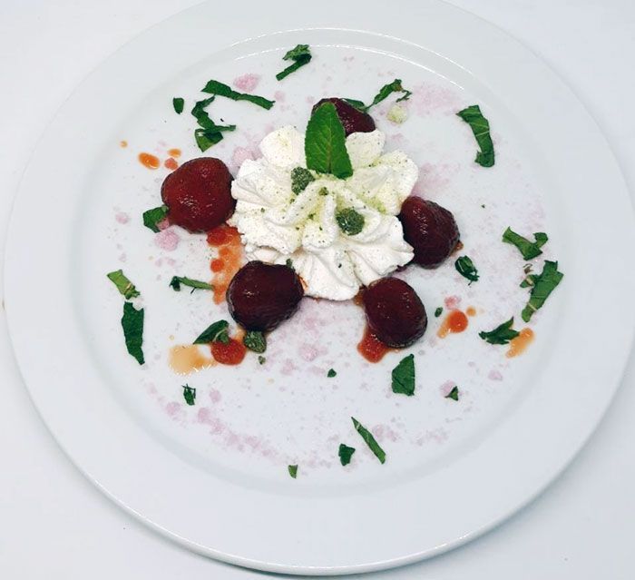 Un plato blanco cubierto con fresas y crema batida.