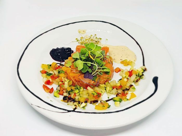 Un plato blanco cubierto con un trozo de carne y verduras.
