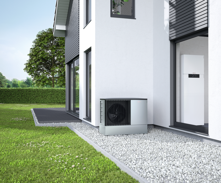 Une personne en salopette bleue installe un climatiseur sur un mur blanc.