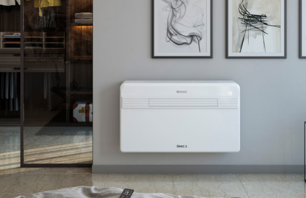 Une main tenant une télécommande pointée vers un climatiseur blanc accroché au mur.