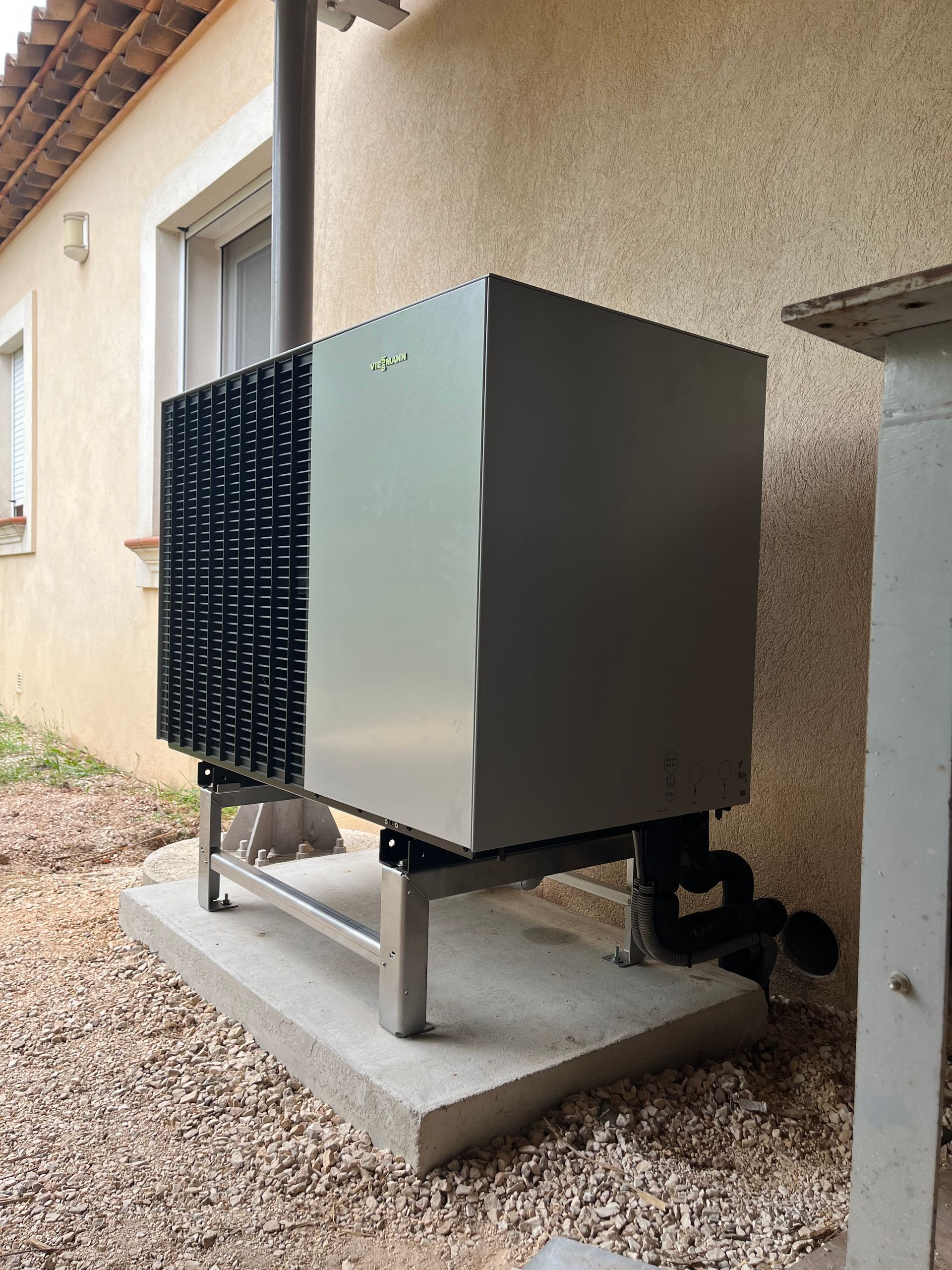 Une unité de pompe à chaleur est installée sur une dalle de béton près d'un bâtiment.