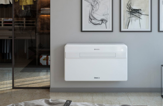 Une personne retire le filtre à air d'un climatiseur mural blanc.