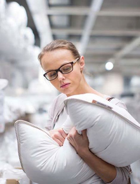 Una mujer que lleva gafas sostiene una almohada blanca.