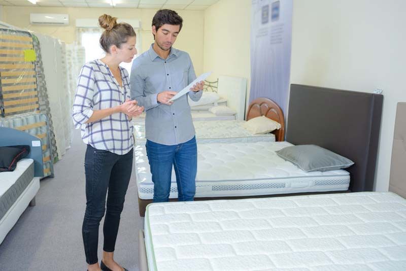 Un hombre y una mujer están mirando un colchón en una tienda de colchones.