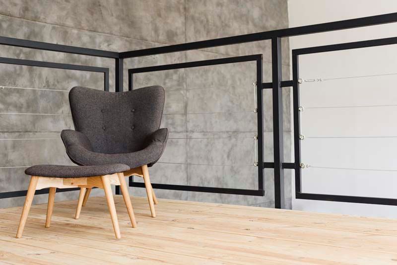 Una silla y una otomana están colocadas sobre un piso de madera en una habitación.