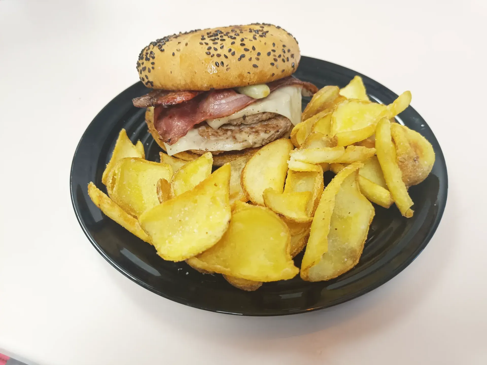 Una hamburguesa y papas fritas en un plato negro