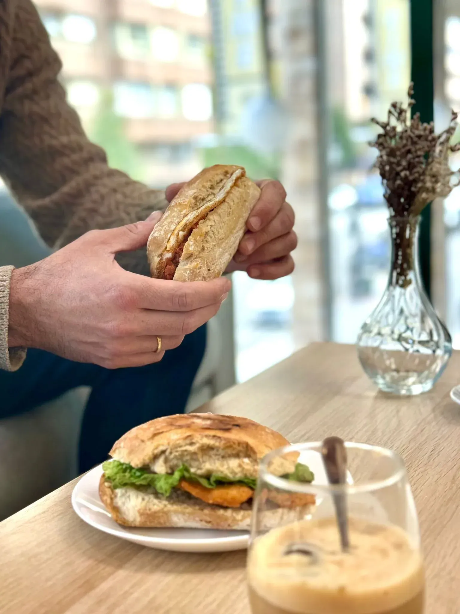Un hombre está sentado en una mesa comiendo un sándwich.