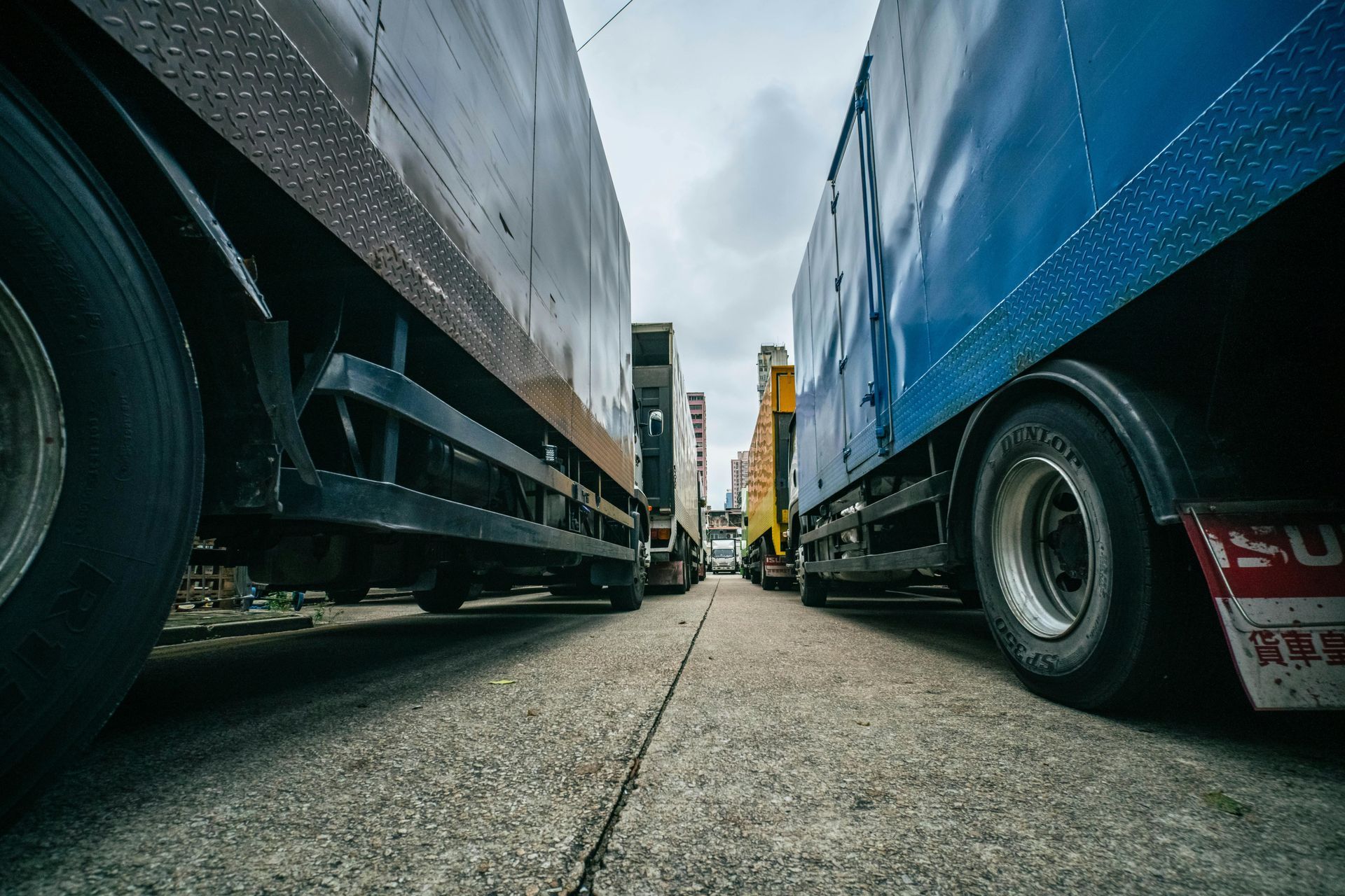 Dos camiones grandes estacionados uno al lado del otro en una carretera gris. Uno es azul y el otro, negro.