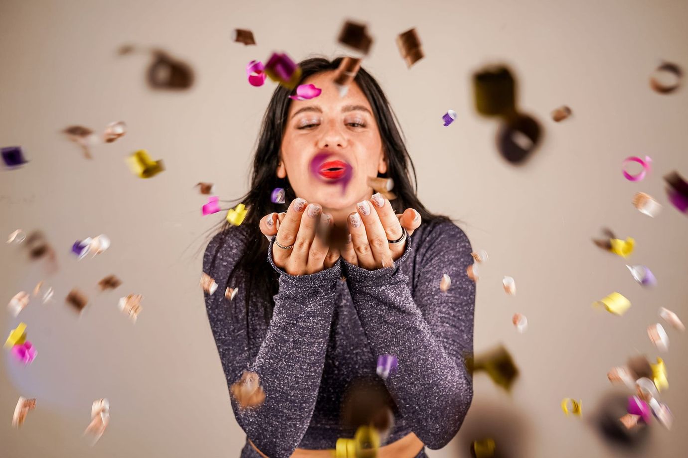 Mujer con top brillante soplando confeti.