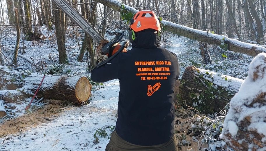 Un ouvrier du bâtiment sourit, tenant une tablette, portant un casque et un gilet de sécurité à l'extérieur.
