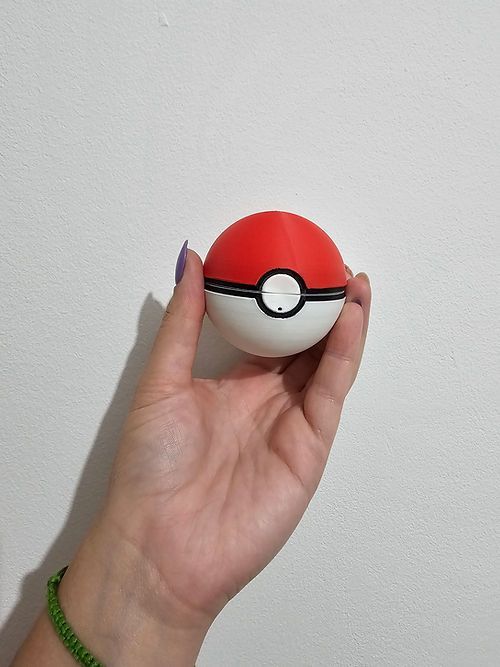 Una persona sostiene una pokebola roja y blanca en su mano.