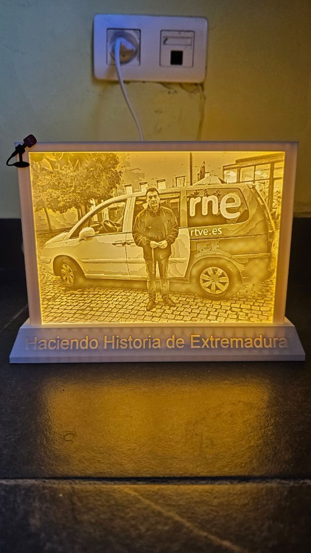 Una fotografía de un hombre parado junto a una camioneta en un marco iluminado.