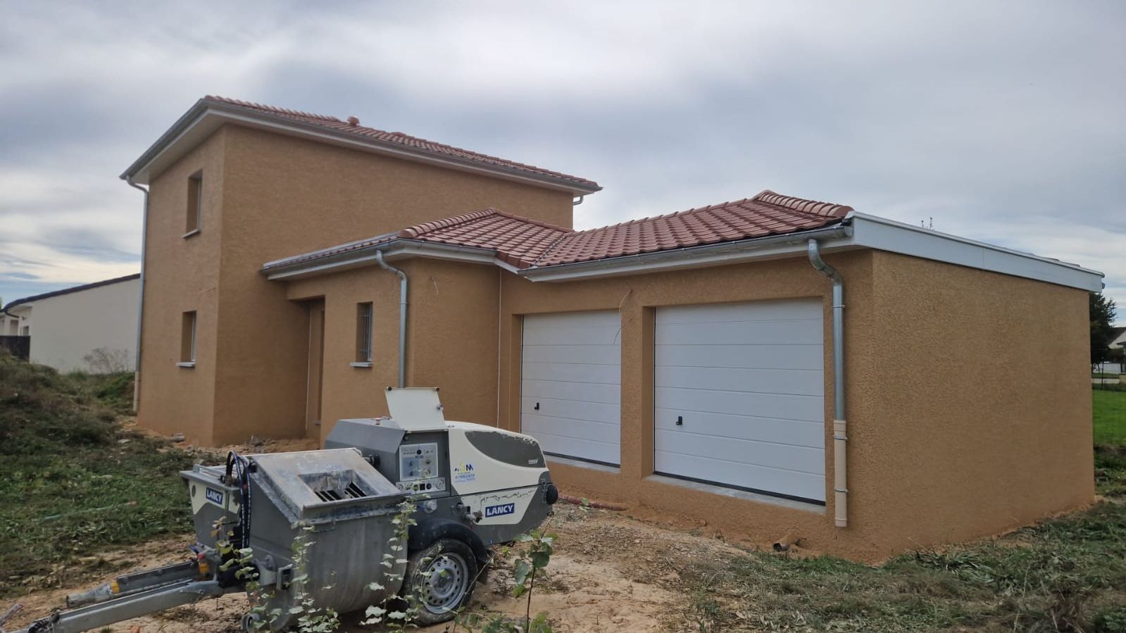 Toiture en construction, avec des piles de tuiles rouges posées sur une ossature en bois. Échelle à droite.