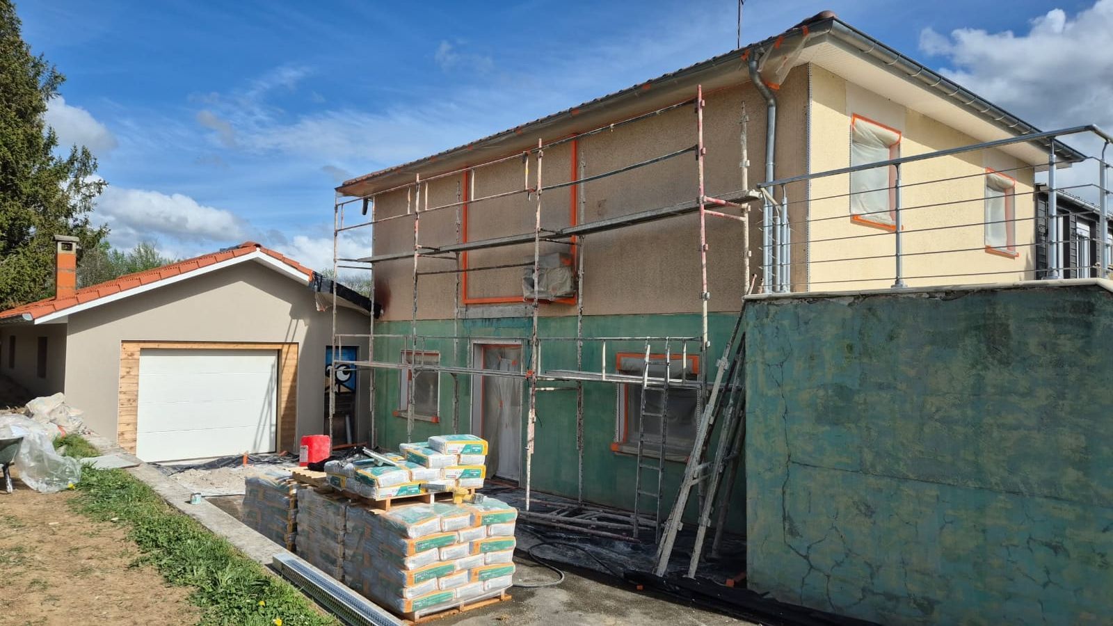 Extérieur d'une maison en construction avec échafaudage. Stuc blanc, fenêtres, ciel bleu.