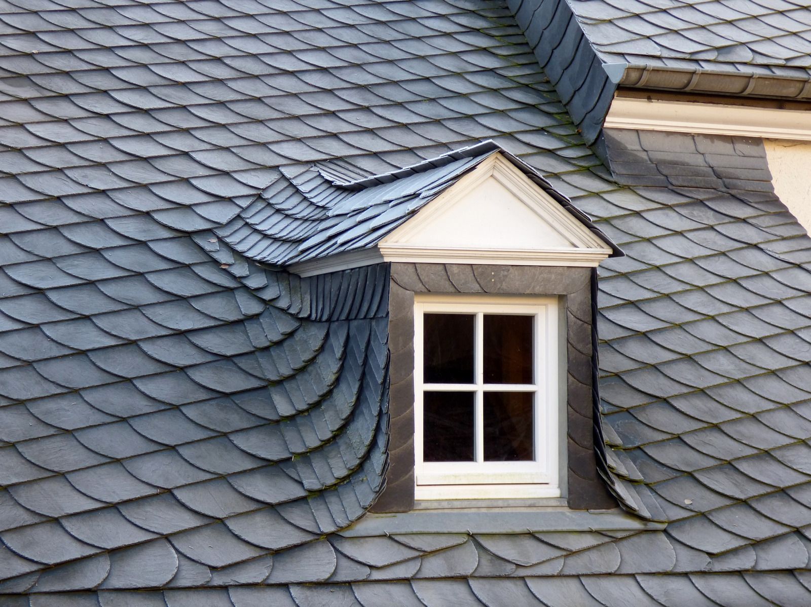 Slate-shingled roof with a dormer window and white trim