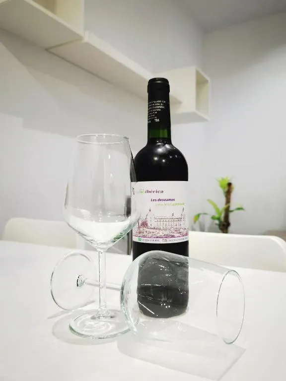 Botella de vino tinto con dos copas sobre una mesa blanca. Decoración interior.