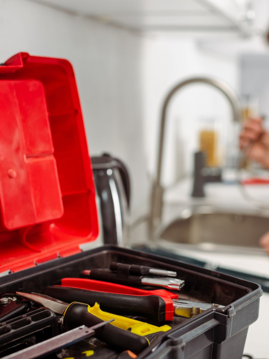 Boîte à outils contenant des tournevis et des pinces près de l'évier de la cuisine