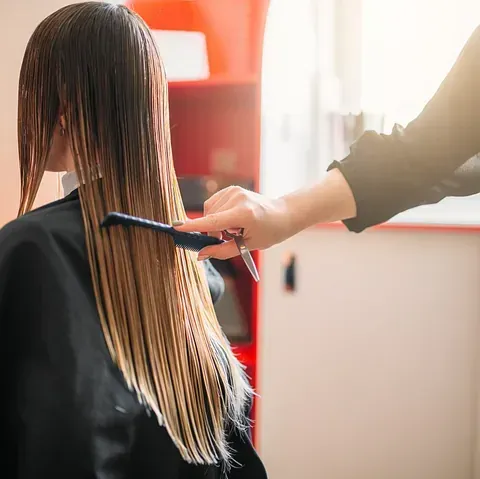 Una mujer se está cortando el pelo en la peluquería.