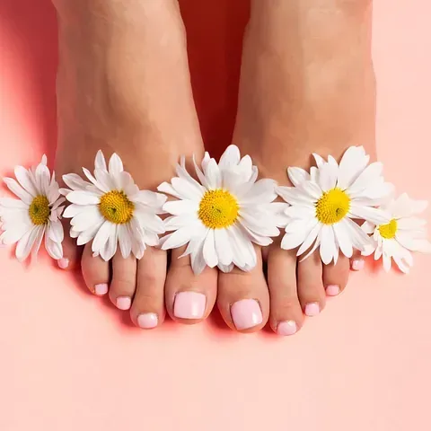 Los pies de una mujer con margaritas sobre un fondo rosa.