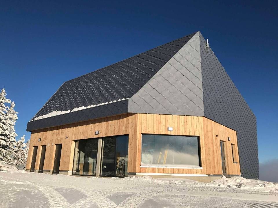 Ein Holzhaus mit grauem Dach und vielen Fenstern, Anton Ulrich GmbH