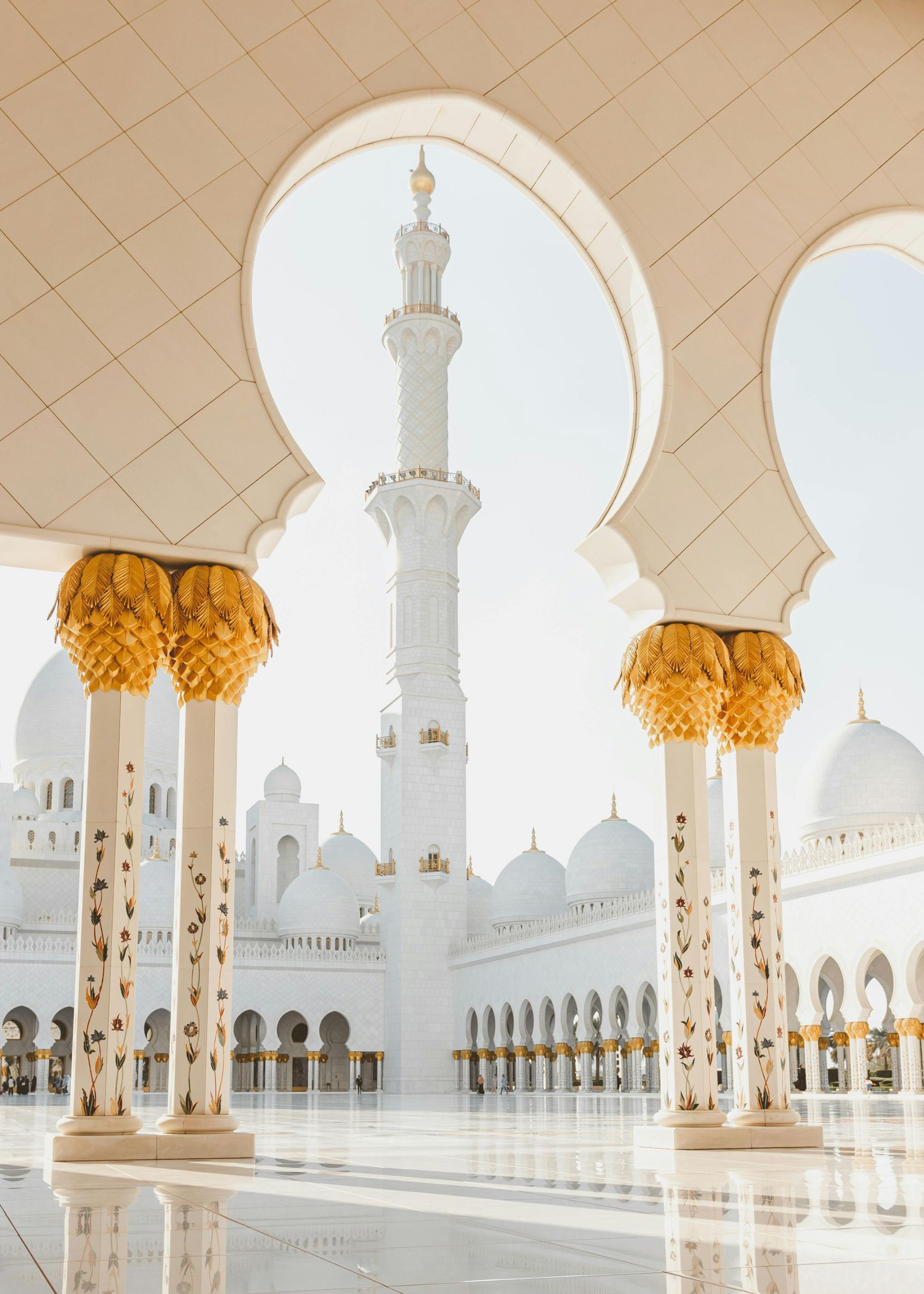 Una mezquita blanca con una torre y arcos delante de ella.