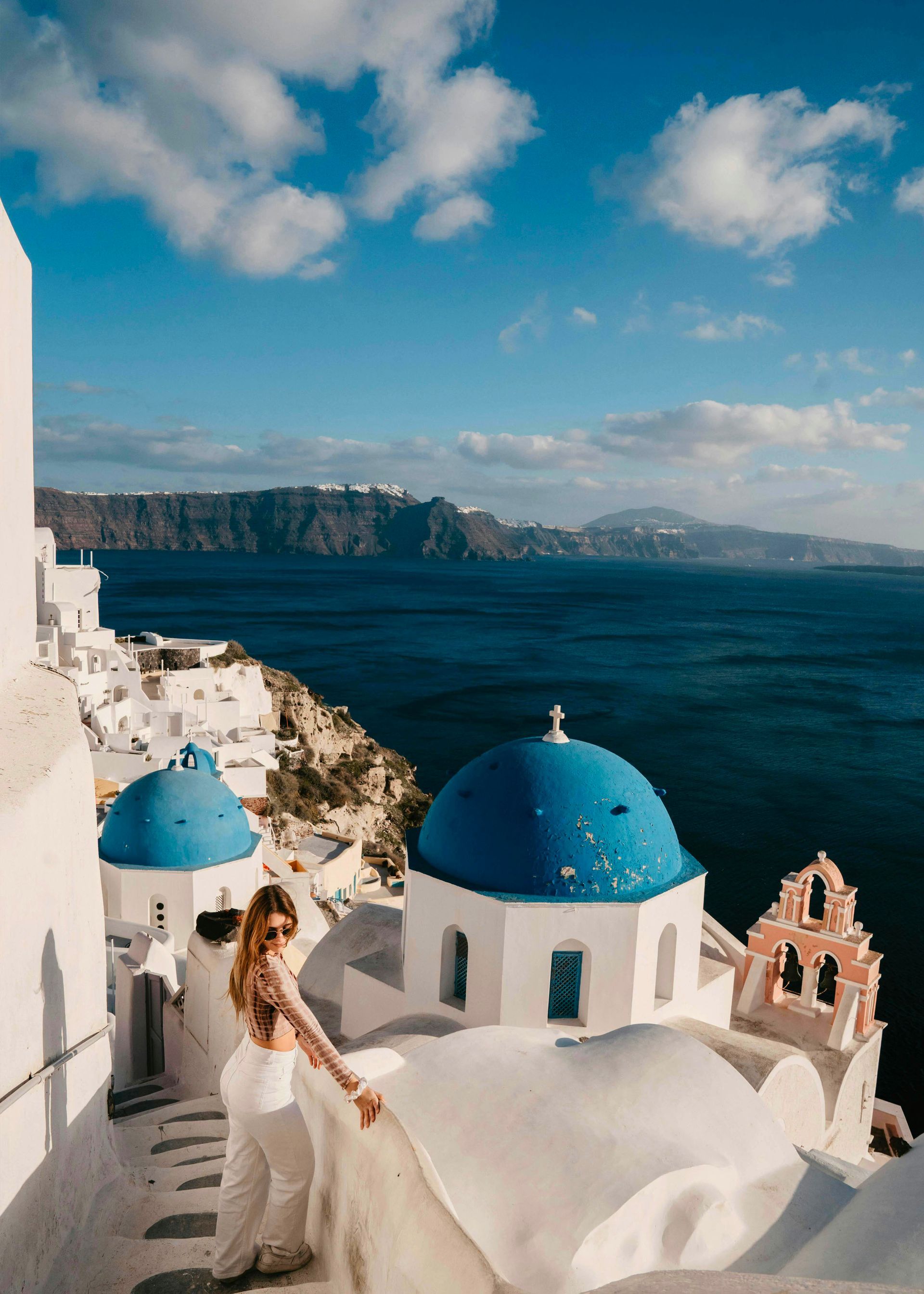 Una mujer con un vestido blanco está parada frente a una cúpula azul.