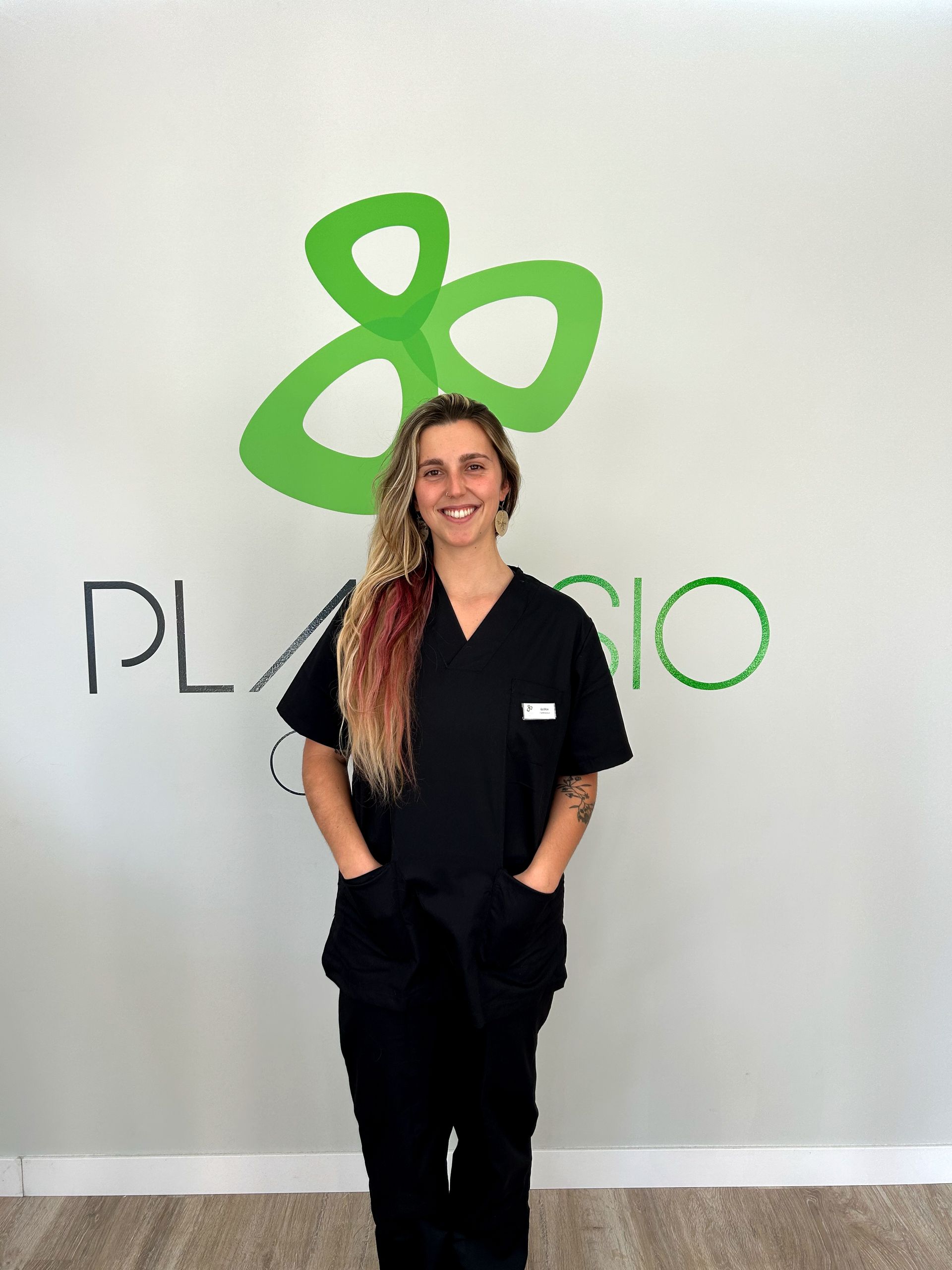 Un hombre con uniforme negro permanece sonriente frente a un logo que dice 