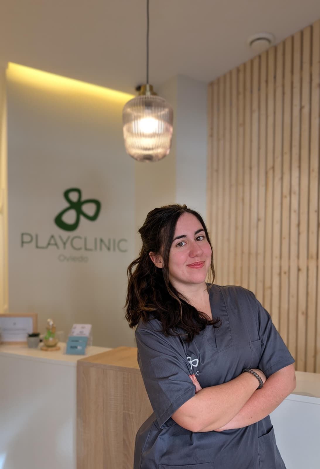 Un hombre con uniforme negro permanece sonriente frente a un logo que dice 