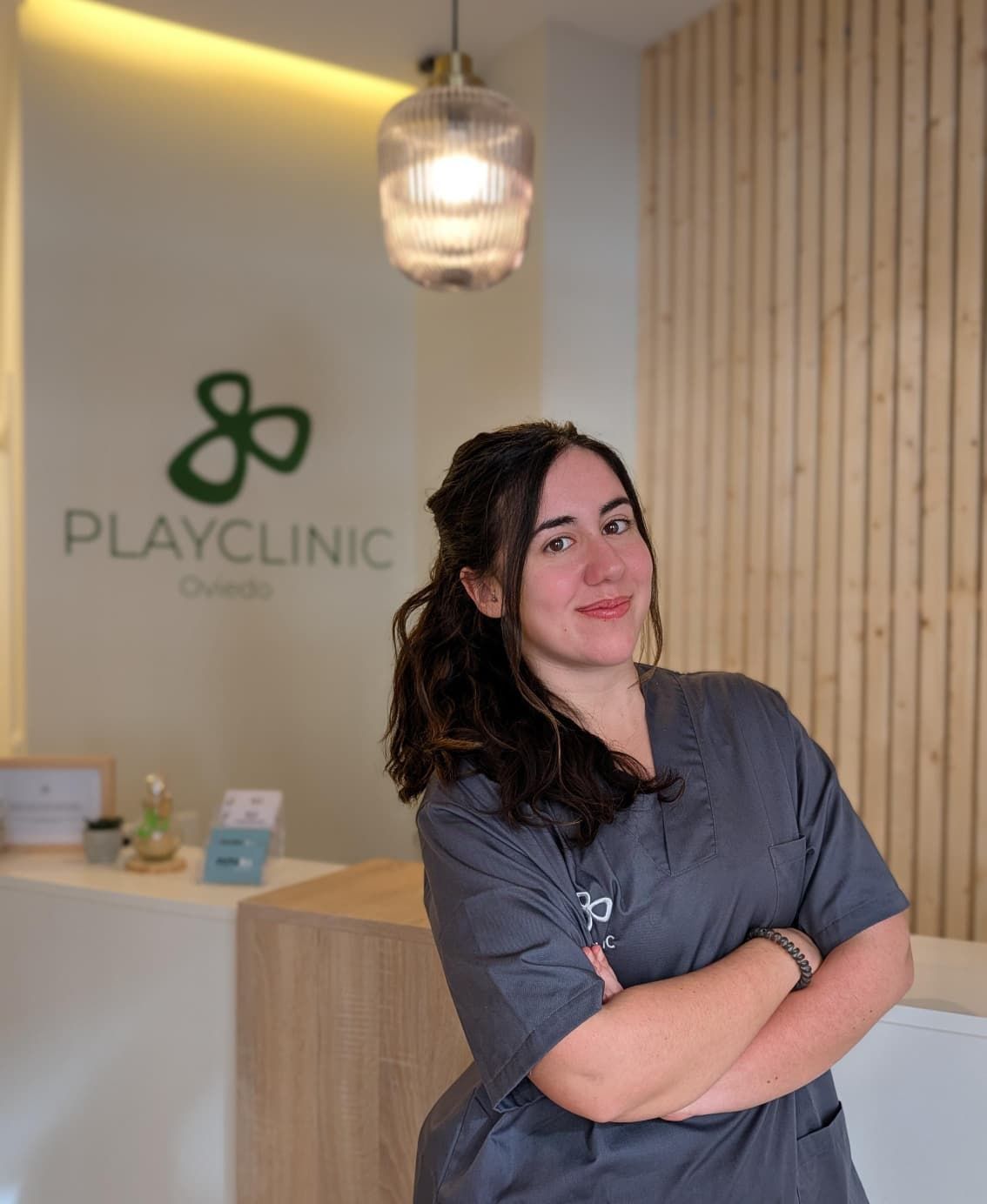 Un hombre con uniforme negro permanece sonriente frente a un logo que dice