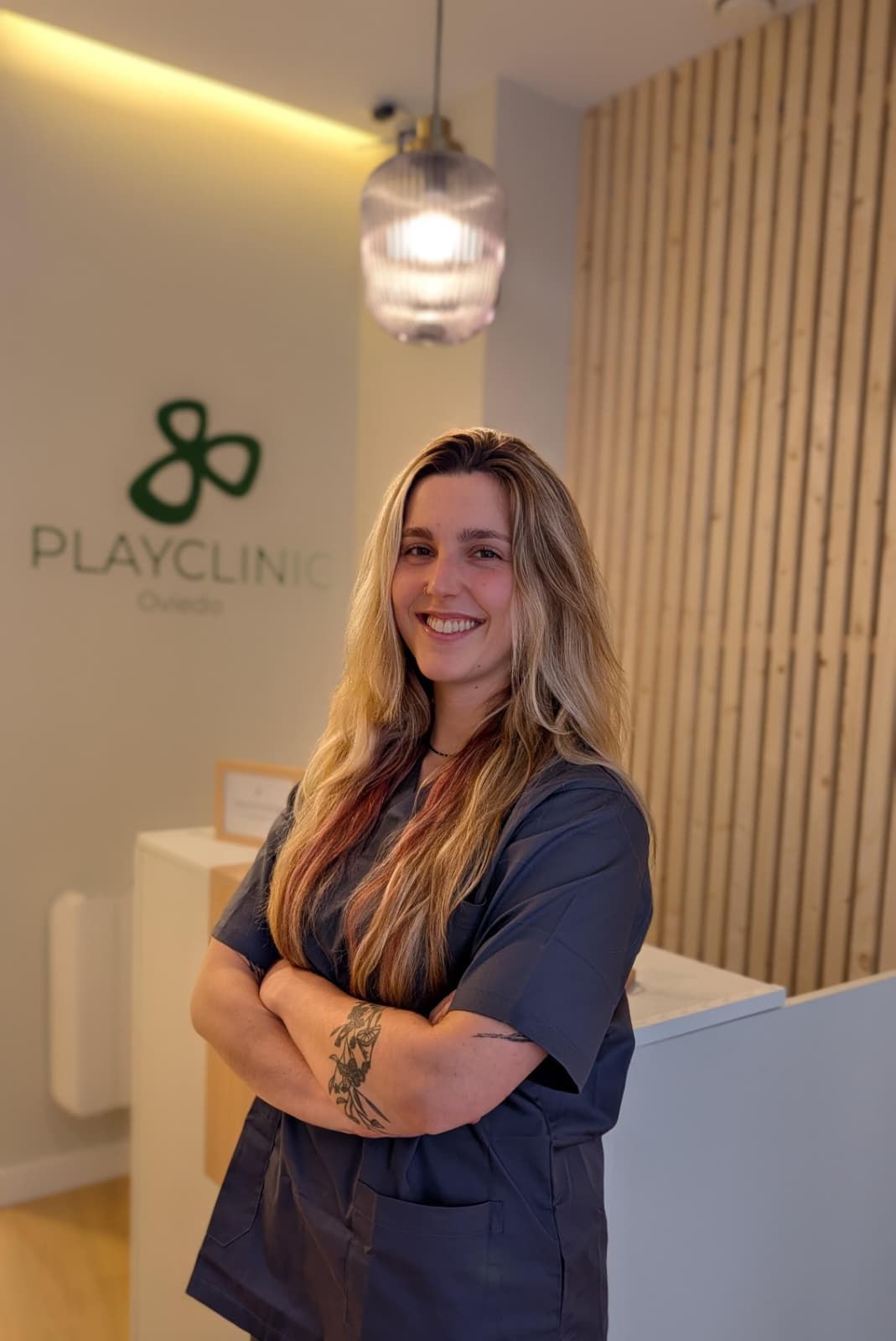 Un hombre con uniforme negro permanece sonriente frente a un logo que dice