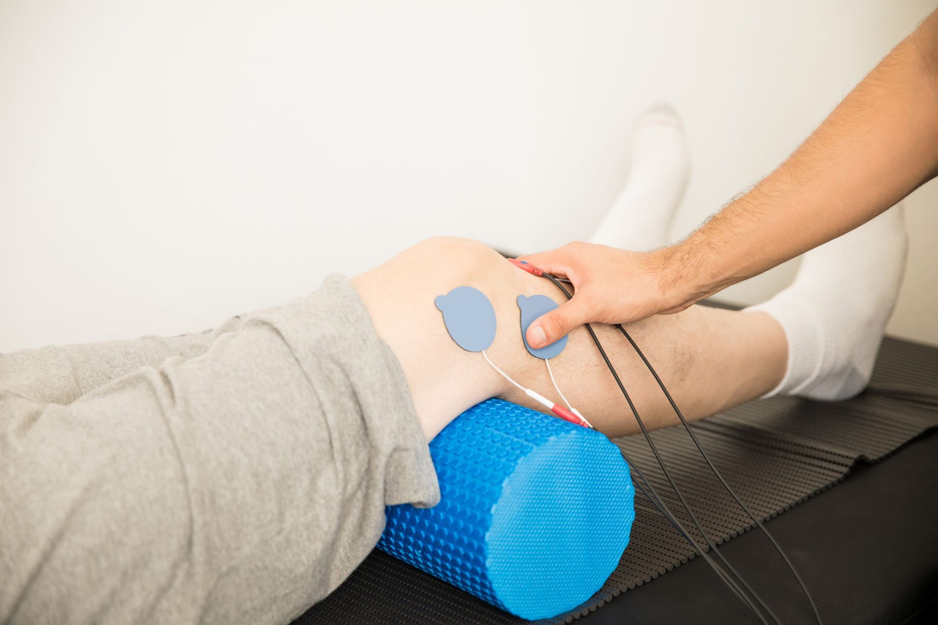 Persona que recibe electroterapia de rodilla con rodillo de espuma azul.
