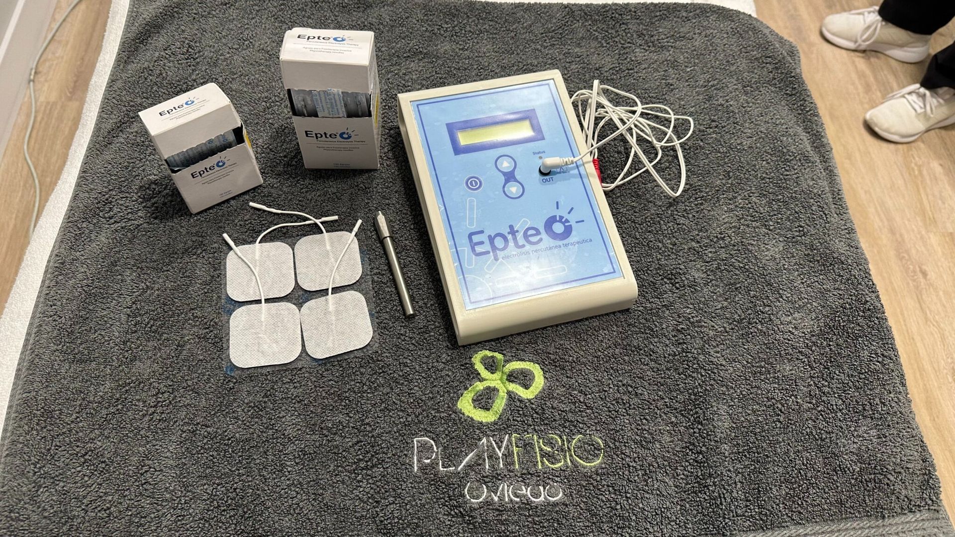 Dispositivo de epieoterapia con almohadillas, sobre una mesa con una toalla; entorno médico.