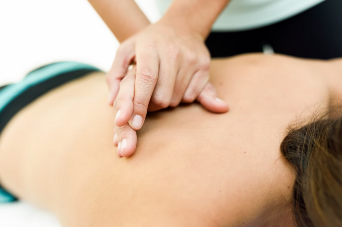 Persona recibiendo masaje de espalda. Las manos del terapeuta apoyan la espalda de una persona boca abajo.
