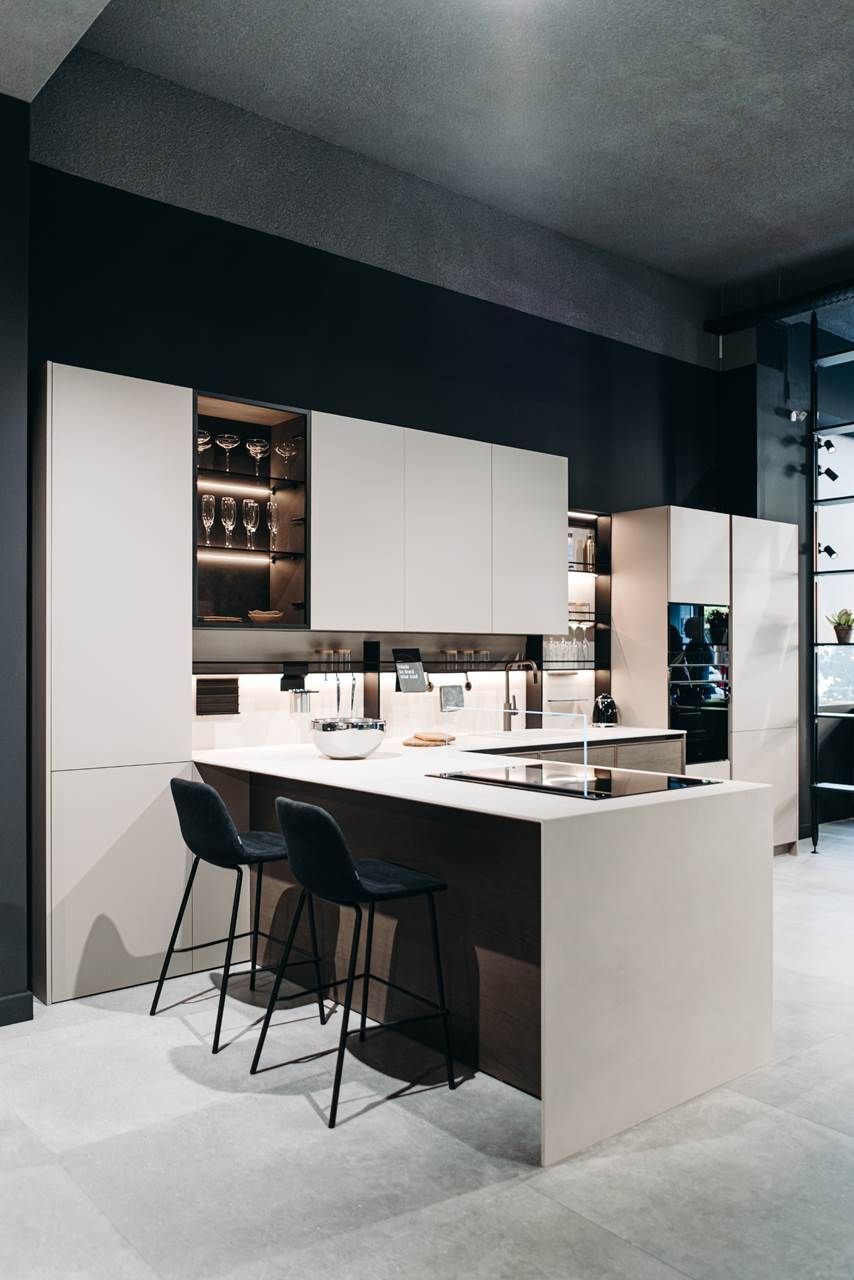 Cocina moderna con gabinetes blancos, isla y dos taburetes de bar negros.