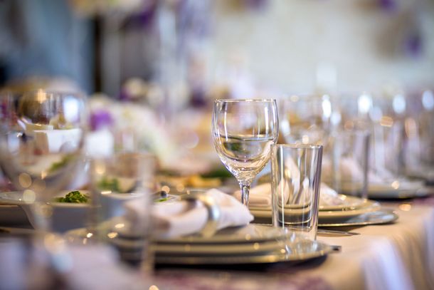 Élégante table dressée avec verres à vin, assiettes et serviettes pliées dans une salle de banquet à l'éclairage tamisé
