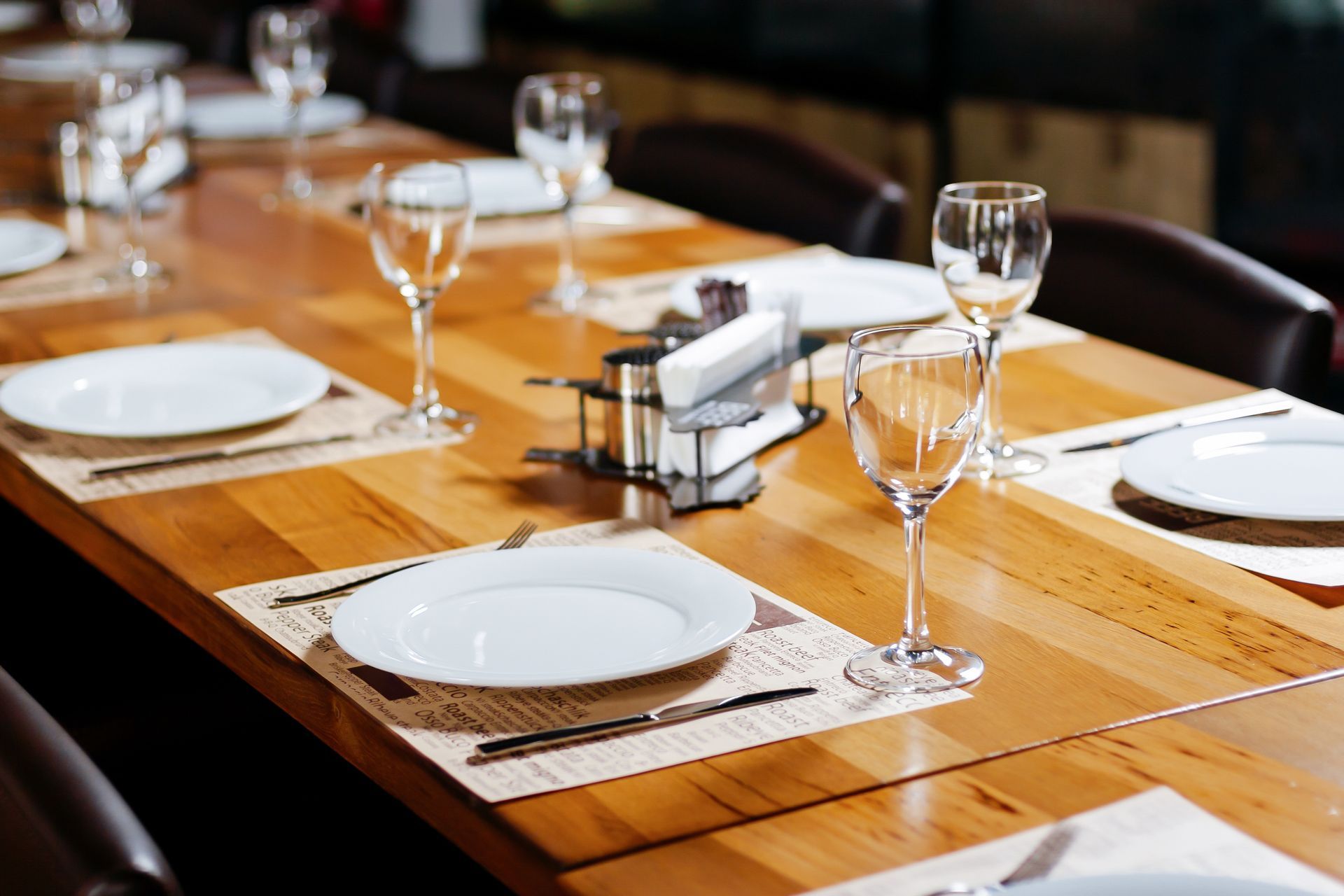 Dresser une table à manger avec des assiettes blanches, des verres à vin et des serviettes sur une table de restaurant en bois