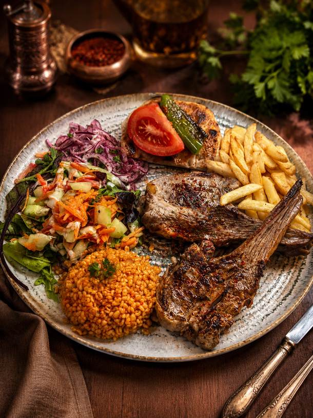 Assiette de viande grillée avec frites, riz, salade et tomate sur une table rustique