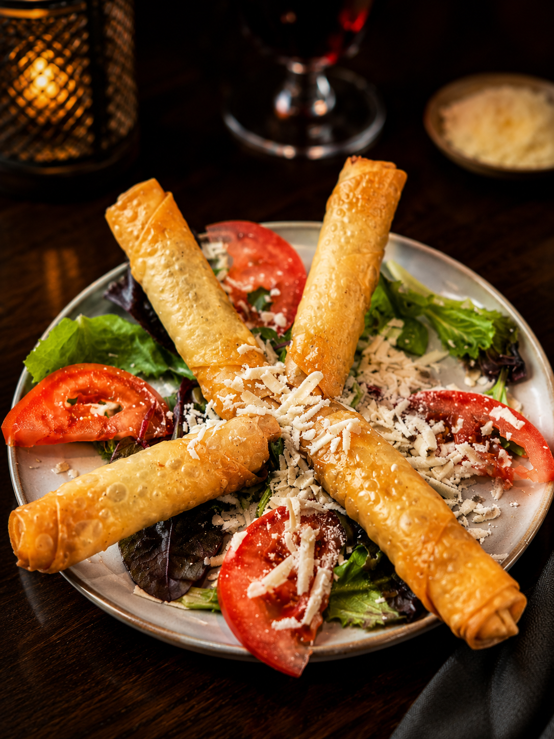 Salade composée de quartiers de tomates, de verdure, de fromage râpé et de quatre gressins dorés.