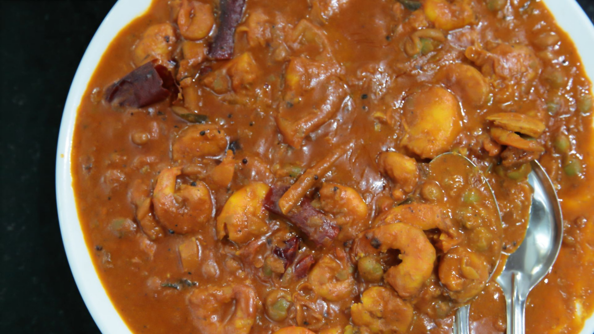 Curry de crevettes servi dans un bol blanc. Sauce aux crevettes, petits pois et épices.